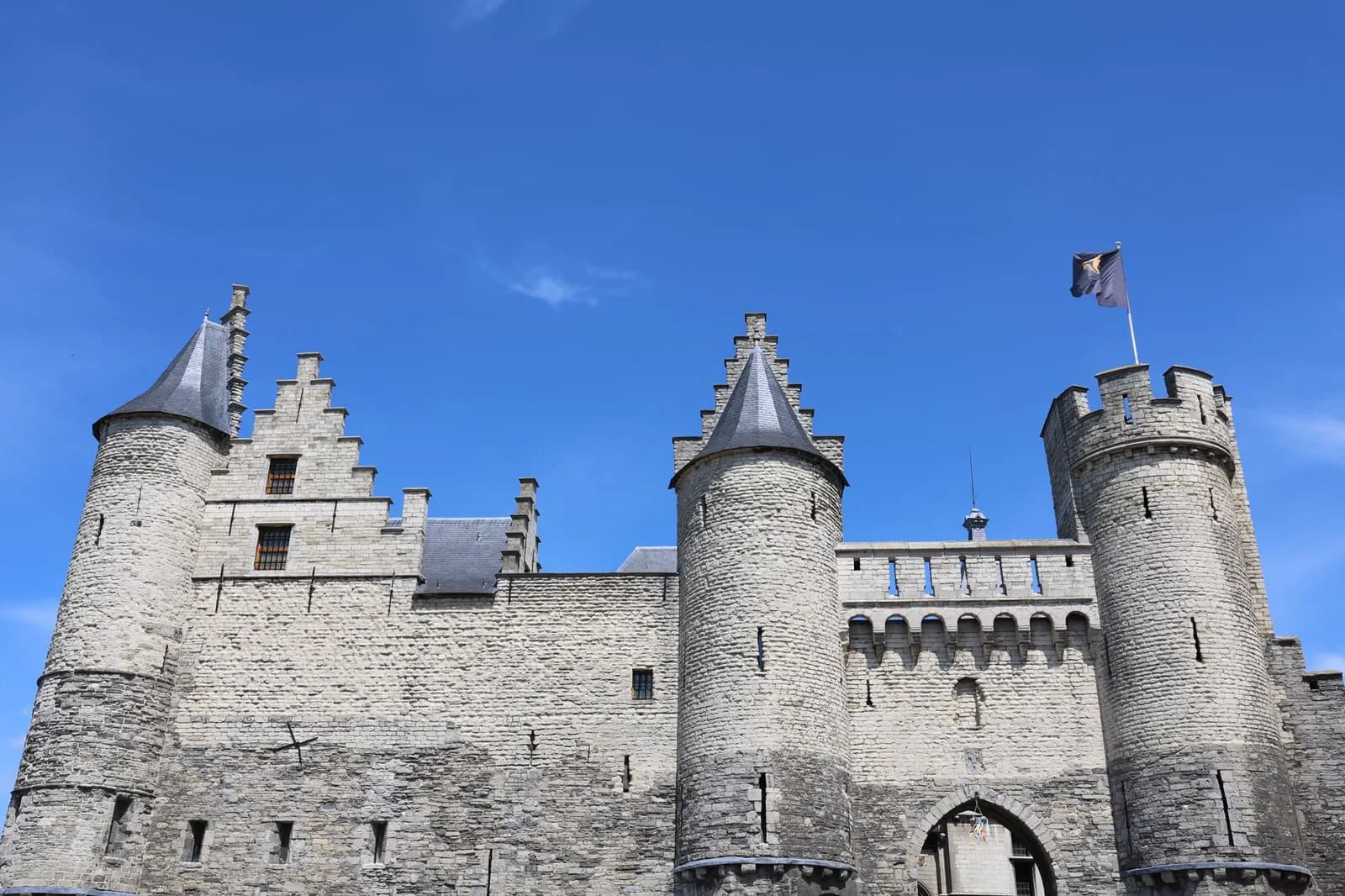 La forteresse de pierre du Steen à Anvers, ses tours rondes et ses pignons à redents sous un ciel bleu
