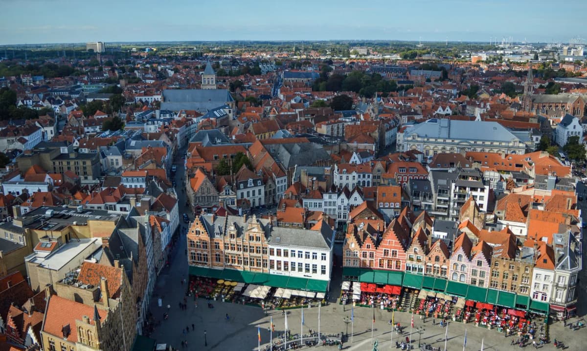 Vue plongeante sur la place du Markt de Bruges et les toits de tuiles rouges de la vieille ville