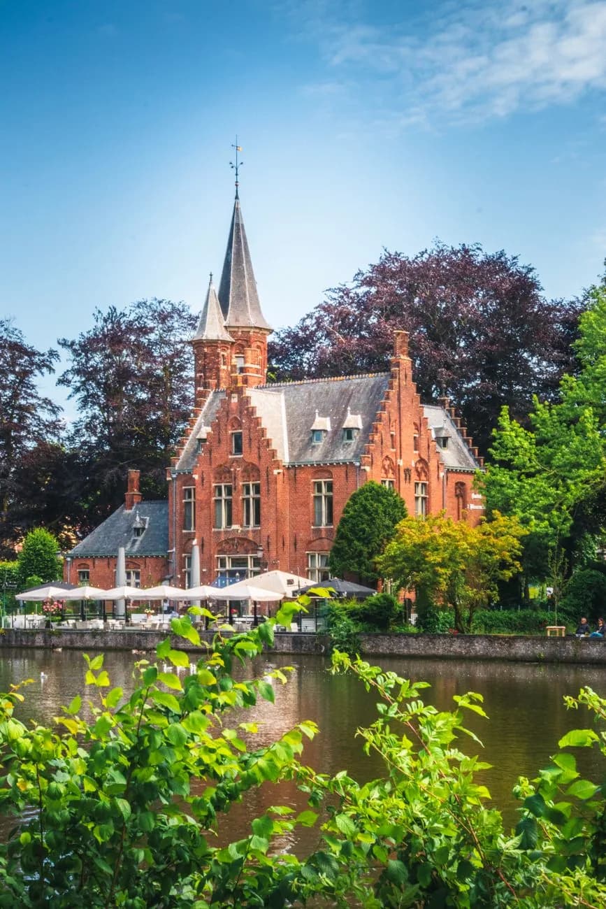 Château néogothique en brique rouge et sa terrasse au bord du lac Minnewater à Bruges