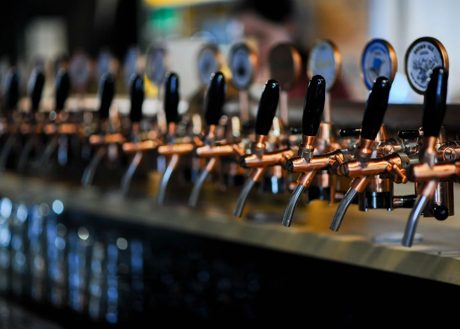 Rangée de tireuses à bière avec leurs manettes noires alignées sur le comptoir d'un bar
