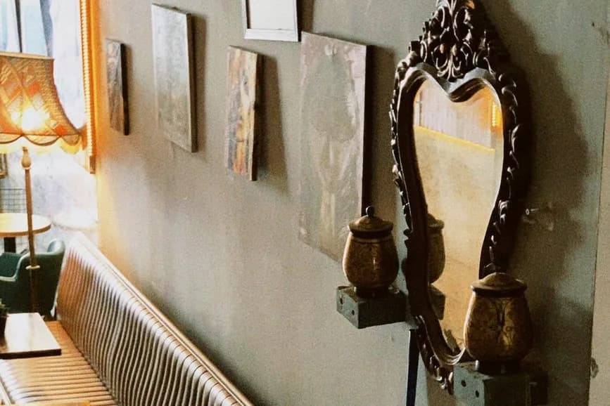Salle de café ancien avec banquette capitonnée, miroir ancien à cadre sculpté et tableaux au mur