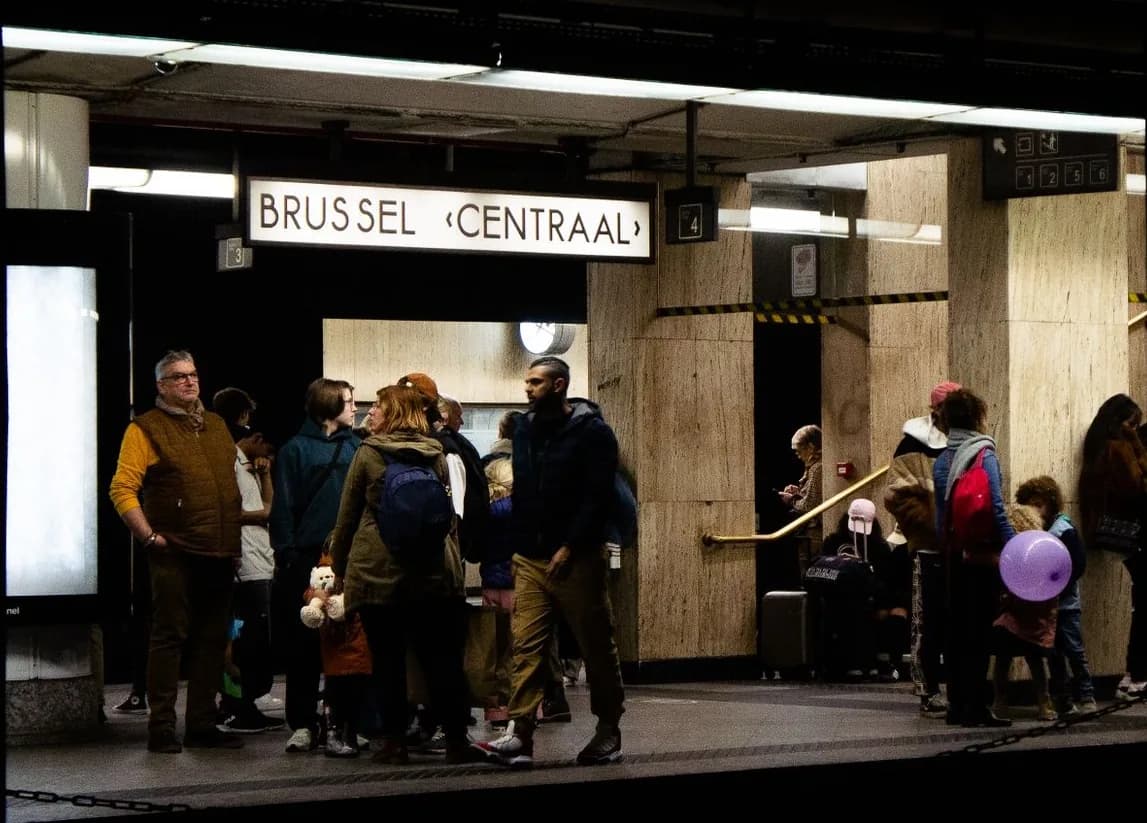 Des navetteurs attendent sur le quai de la gare de Bruxelles-Central, sous le panneau Brussel-Centraal