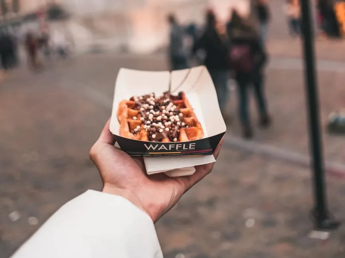 Gaufre de Bruxelles rectangulaire nappée de chocolat, tenue dans la rue