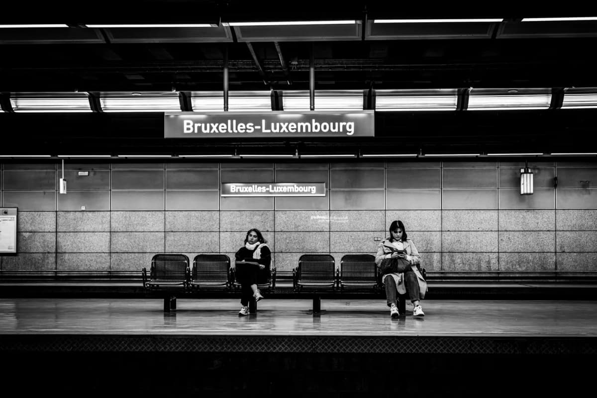 Deux voyageuses sur le quai de la gare Bruxelles-Luxembourg, au pied du quartier européen, en noir et blanc