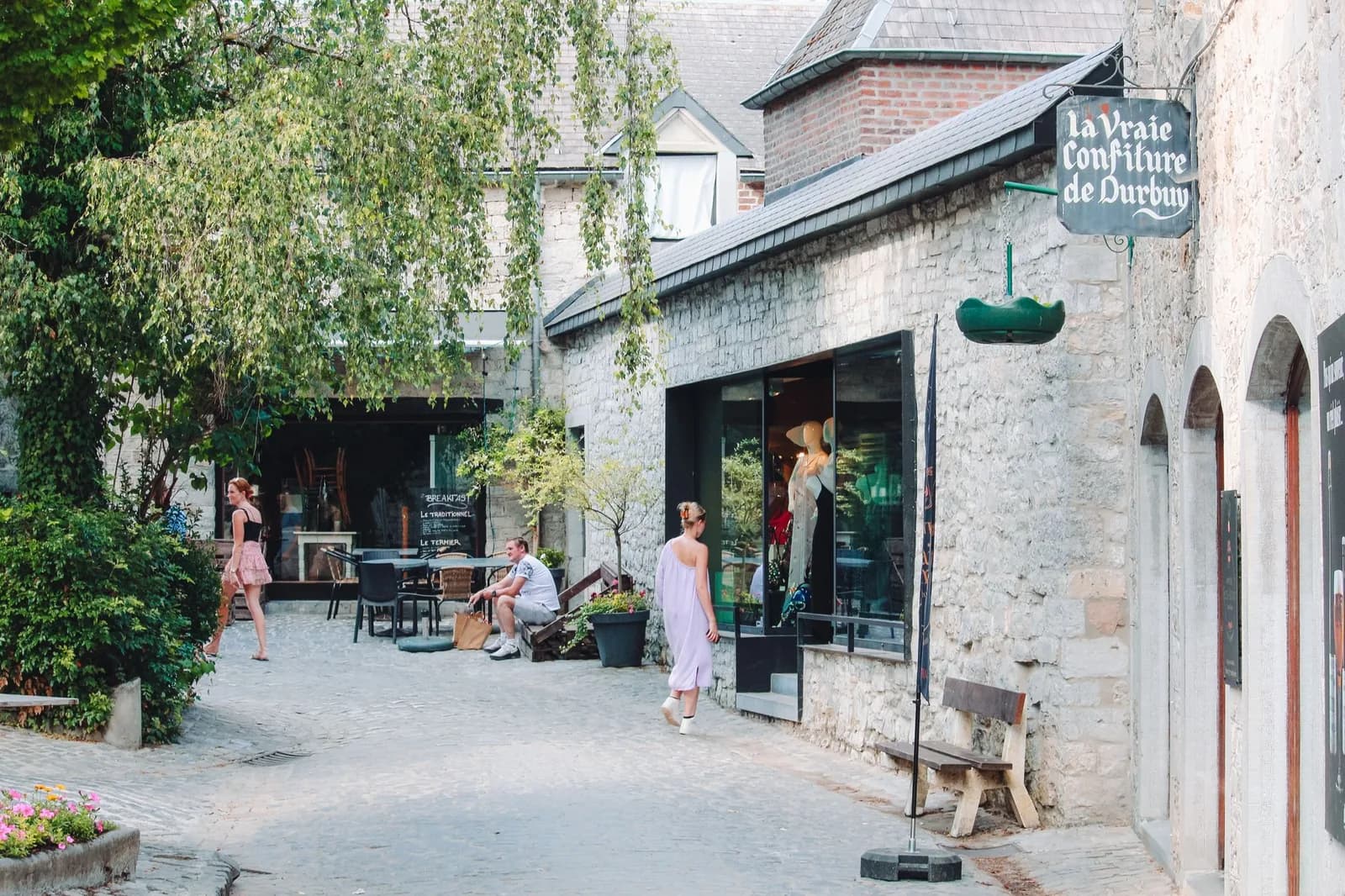 Ruelle pavée de Durbuy avec des boutiques, une terrasse de café et l'enseigne « la Vraie Confiture de Durbuy »