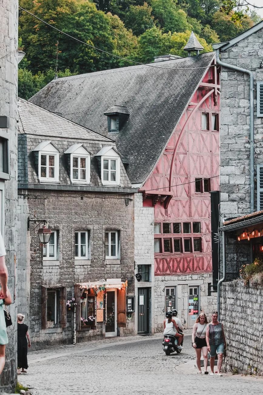 Ruelle pavée de Durbuy bordée de maisons en pierre grise et d'une façade à colombages peinte en rose