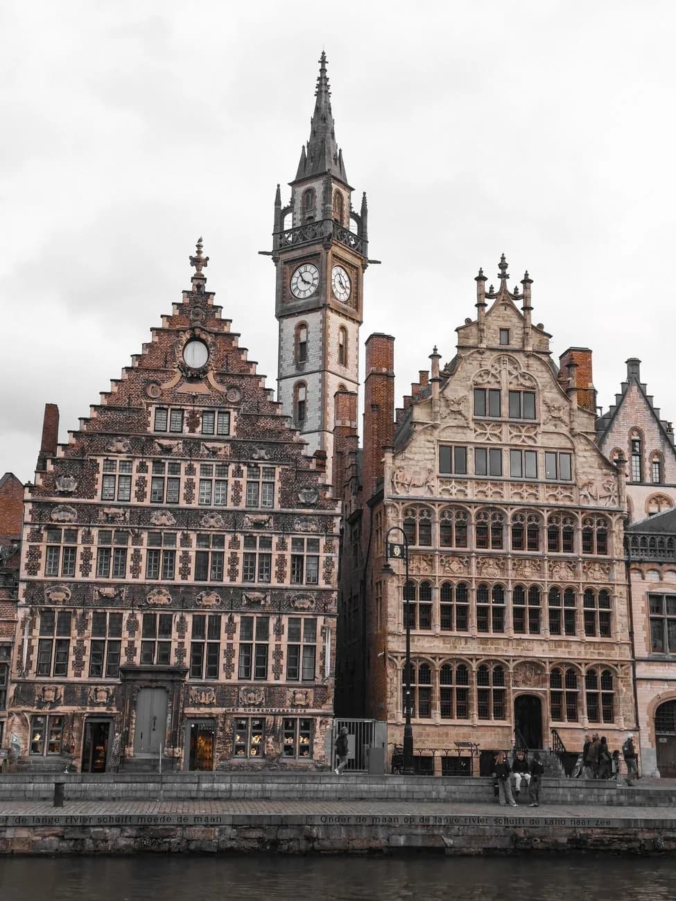 Façades gothiques du Graslei à Gand, dont le Coorenmetershuys, devant le quai gravé d'un vers en néerlandais