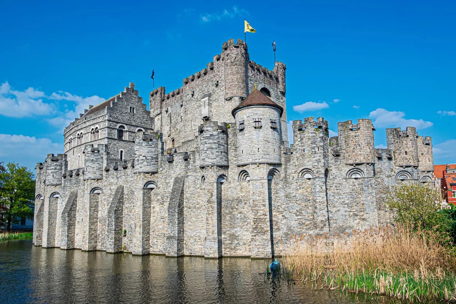 Le château des Comtes de Gand, ses tourelles et ses créneaux de pierre grise au-dessus des douves