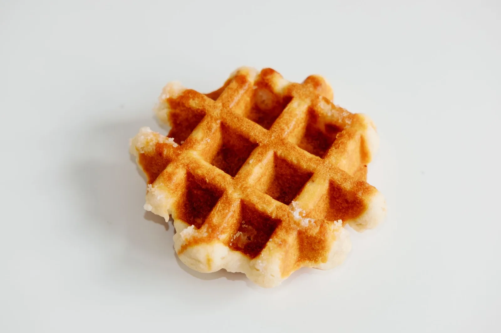 Une gaufre de Liège dorée, les grains de sucre perlé visibles sur ses bords