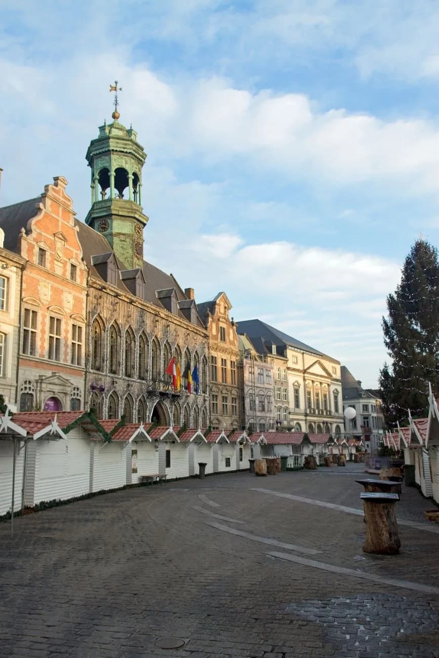 L'hôtel de ville gothique de Mons et son campanile vert, devant les chalets d'un marché de Noël