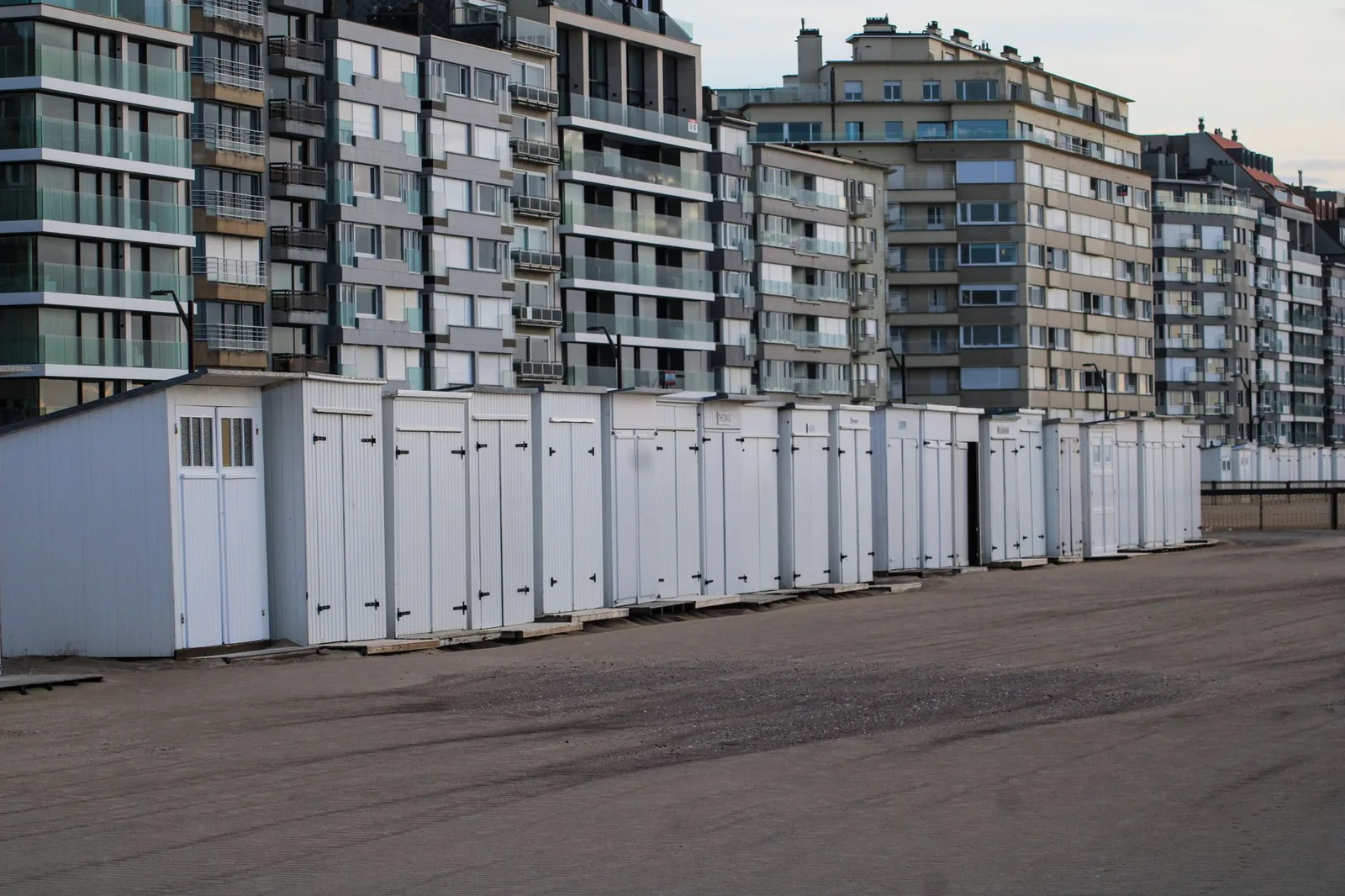 Rangée de cabines de plage blanches sur le sable devant les immeubles modernes du front de mer de Knokke-Heist