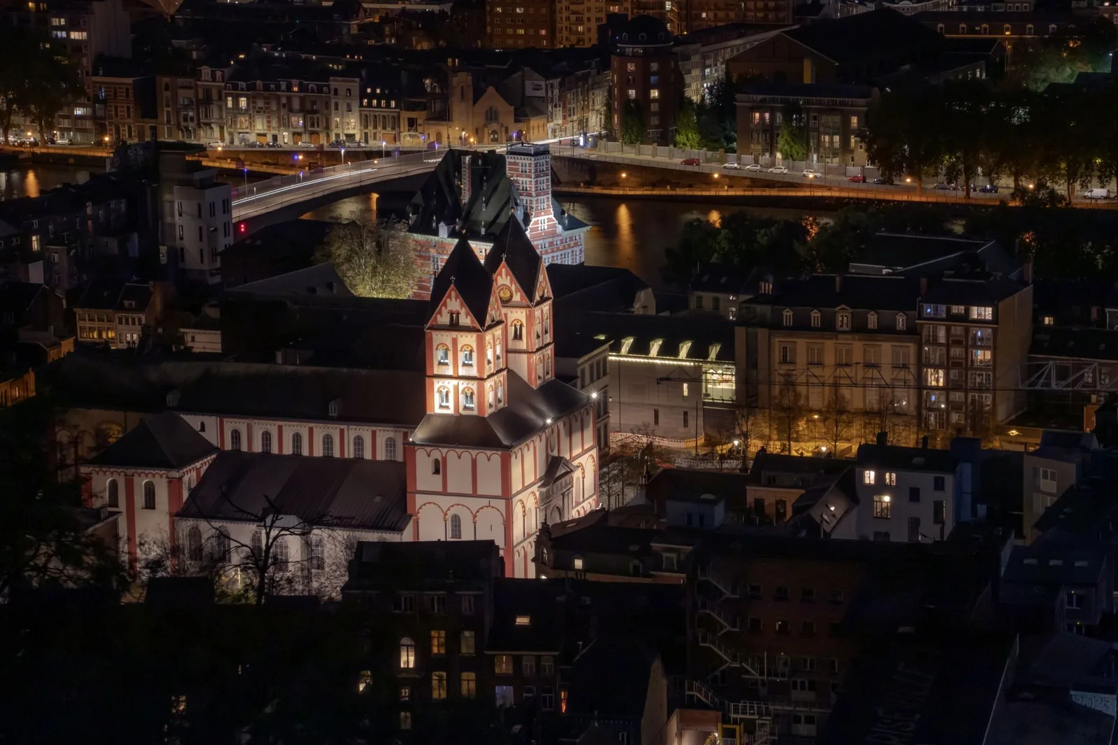 Vue de nuit sur les quais de la Meuse à Liège, une église romane éclairée au-dessus des toits