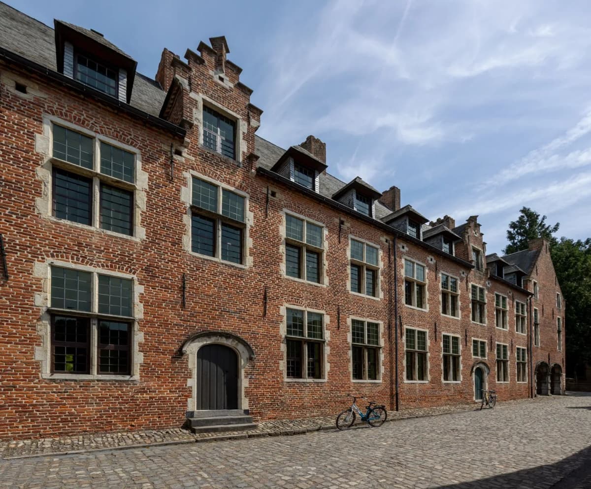 Maisons de brique rouge à pignons à gradins du Grand Béguinage de Louvain, rue pavée et vélo