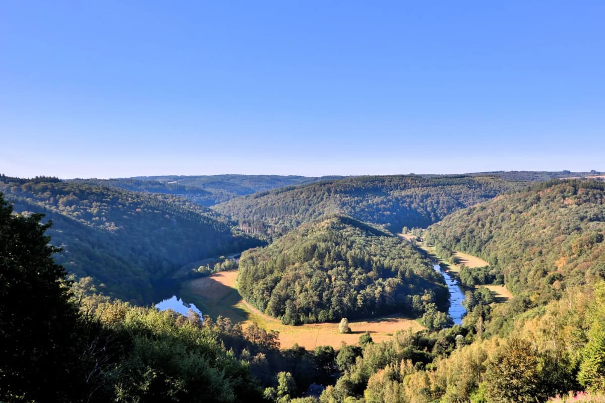 Méandre d'une rivière enserrant un éperon boisé, au milieu de collines couvertes de forêt