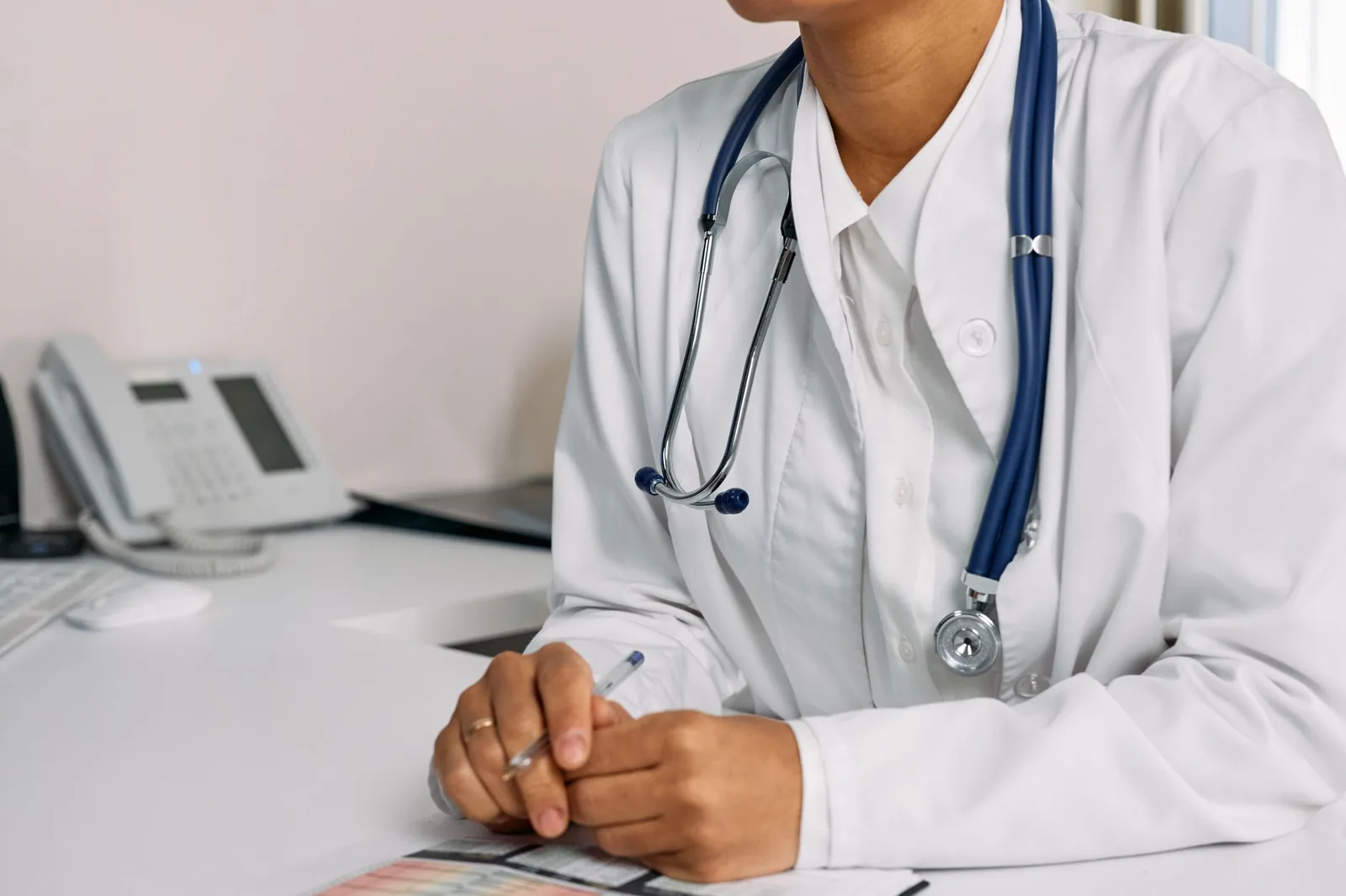 Une médecin en blouse et stéthoscope, assise à son bureau de consultation