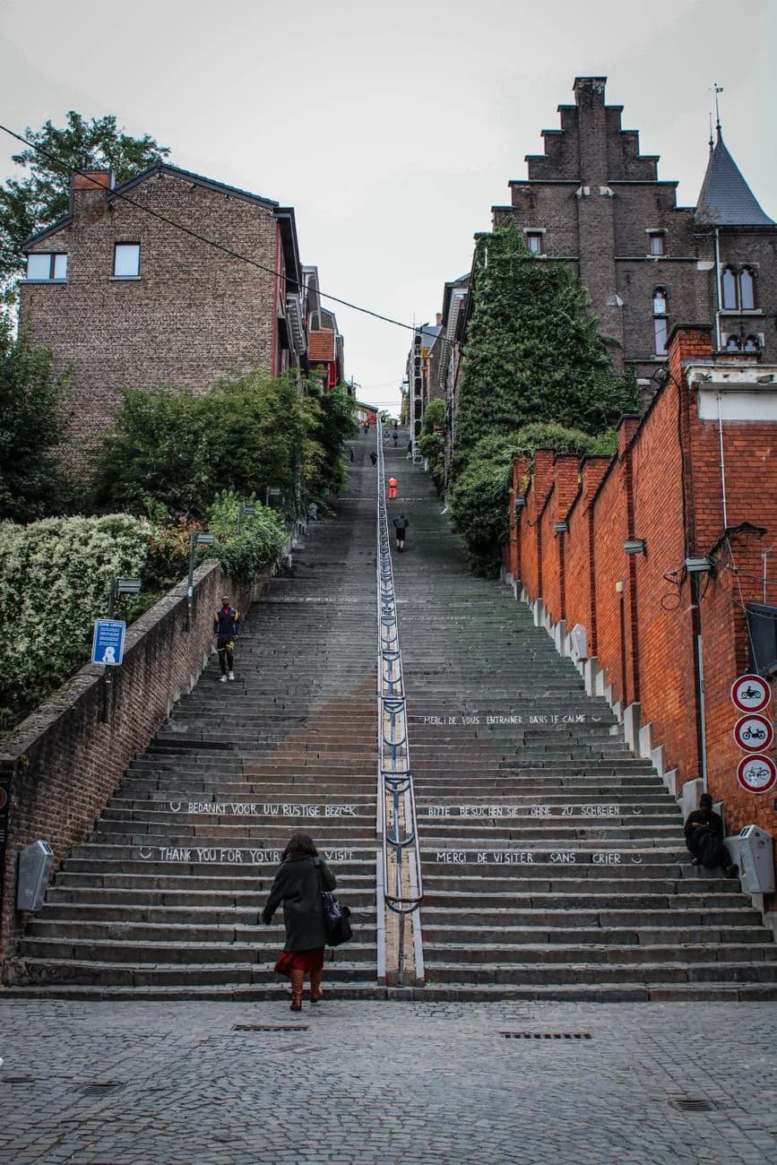 L'escalier de la Montagne de Bueren à Liège, ses marches couvertes d'inscriptions à la craie et le mur de brique qui le borde