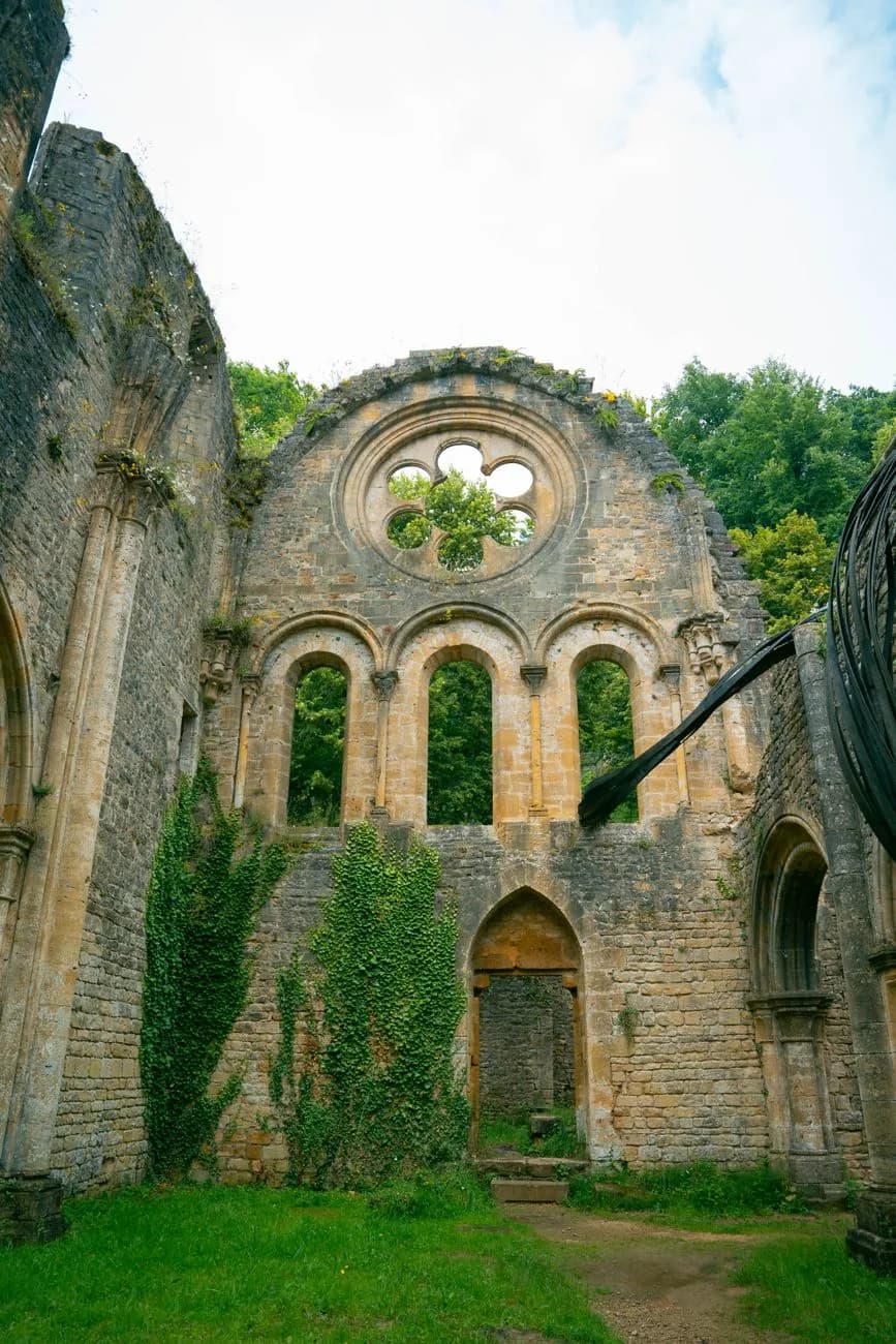 Le pignon des ruines de l'église abbatiale d'Orval, sa rosace ouverte sur les arbres et le lierre sur les murs