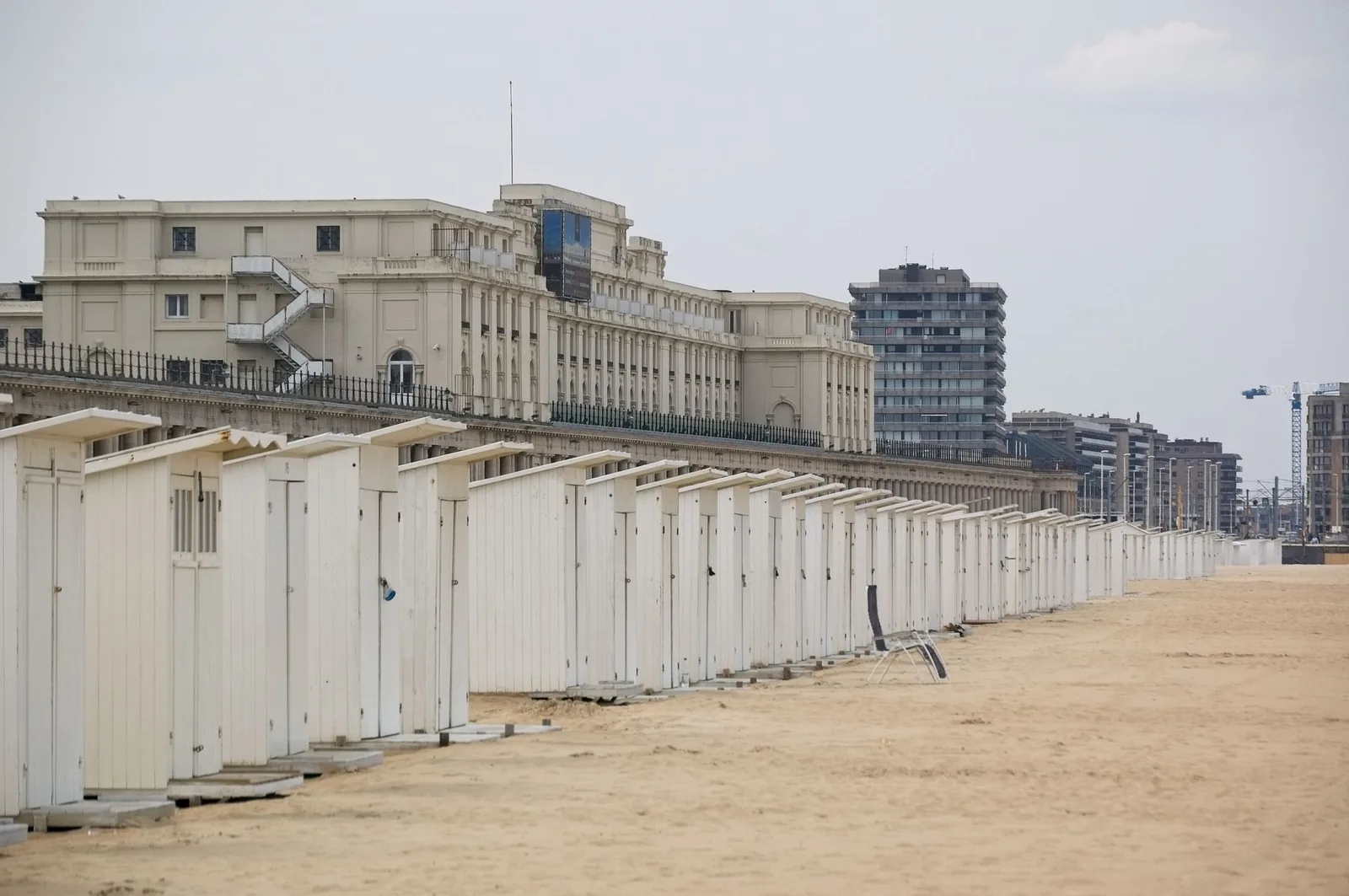 Rangée de cabines de plage blanches sur le sable d'Ostende, au pied des Galeries royales et de la façade du Thermae Palace
