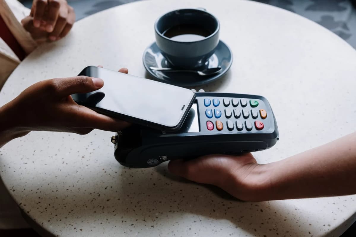 Paiement sans contact avec un smartphone posé sur un terminal de carte, à une table de café