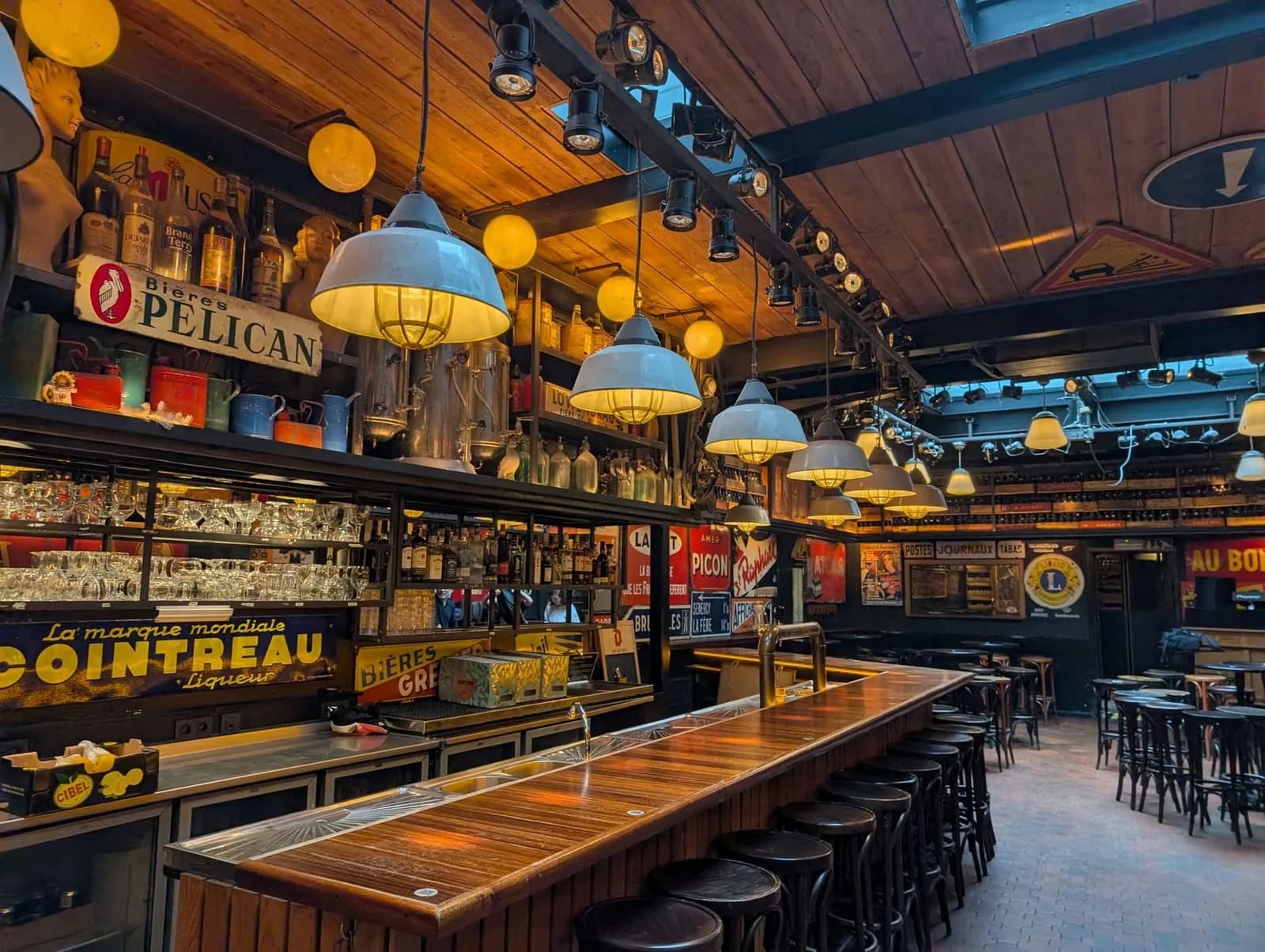 Intérieur chaleureux d'un vieux pub avec plafond en bois, lampes suspendues, longs comptoirs et enseignes anciennes