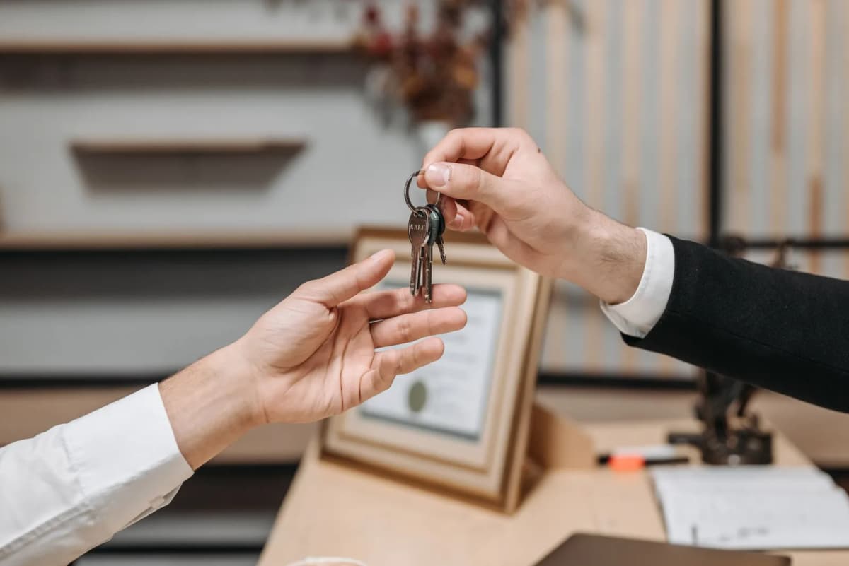 Remise des clés d'un logement loué, d'une main à l'autre au-dessus d'un bureau d'agence