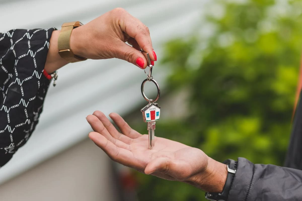 Remise d'une clé de maison avec un porte-clés en forme de maisonnette, de main à main