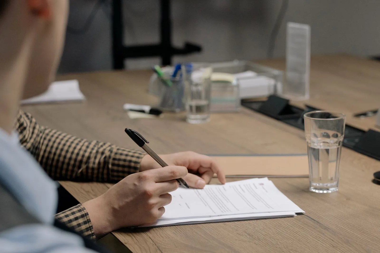 Une personne remplit un formulaire papier à une table de bureau