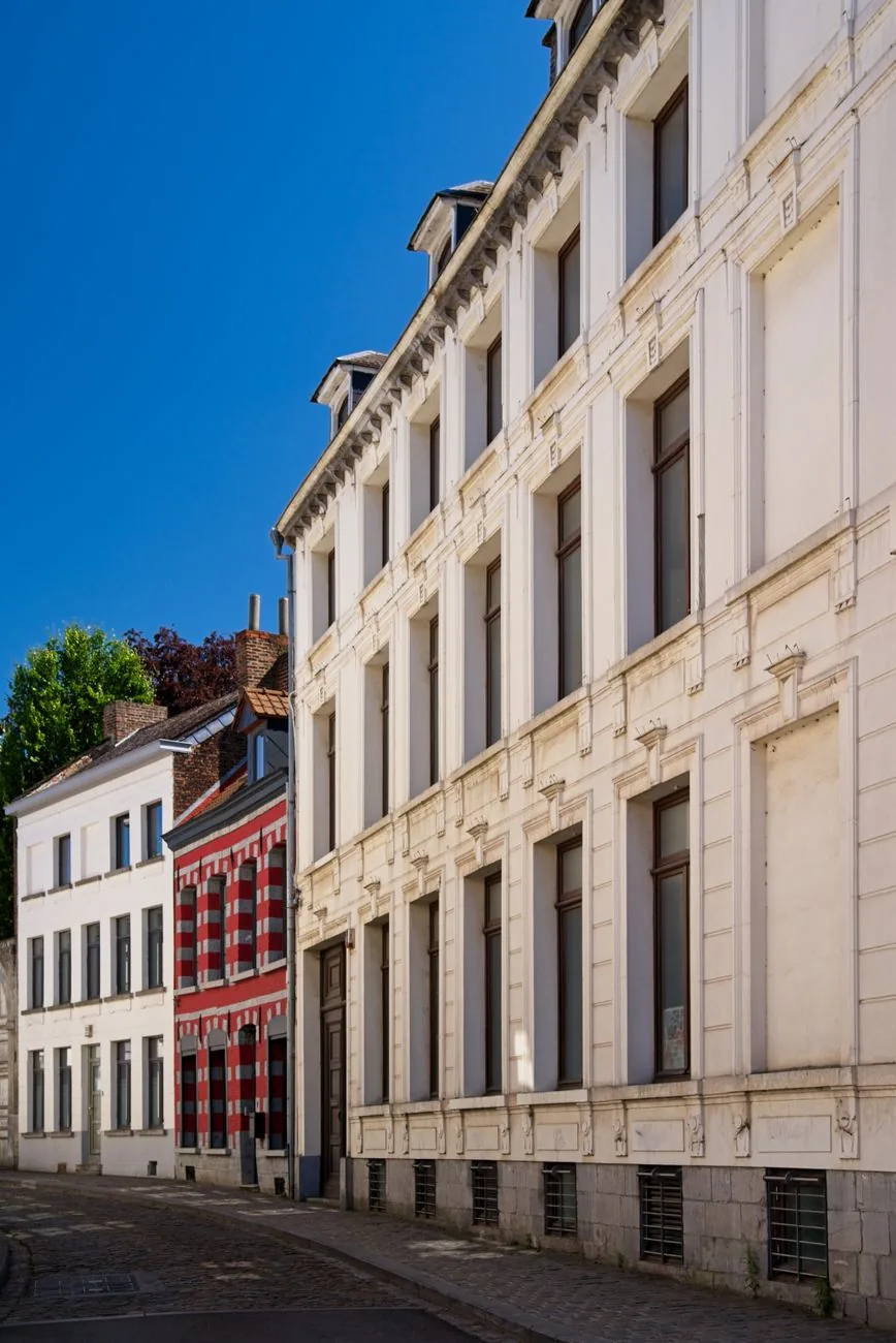 Rue en pente bordée d'une longue façade classique blanche et de maisons en brique