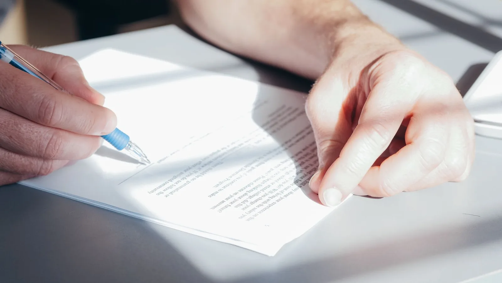 Gros plan sur une main qui signe un document posé sur une table