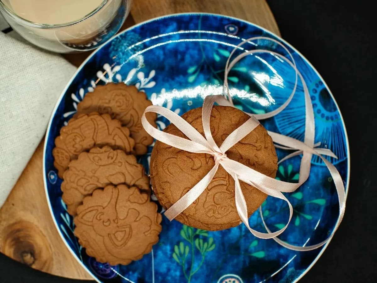 Speculoos sur une assiette bleue, dont une pile nouée d'un ruban, sur une planche en bois