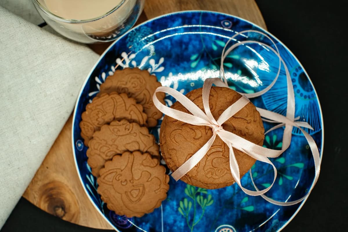 Biscuits aux épices de type spéculoos sur une assiette bleue décorée, nouée d'un ruban